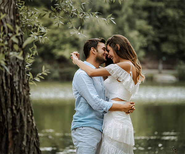 Glückliches Paar umarmt sich in der Nähe eines Sees und feiert seine Hochzeit.