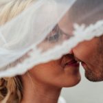 Braut und Bräutigam küssen sich unter einem Schleier