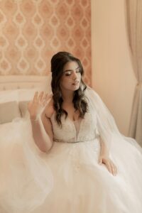 Getrennte Familien beim Hochzeitstag vereint. Braut im Brautkleid, mit geschlossenen Augen, auf einem Bett sitzend.