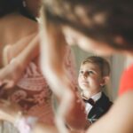 Ein kleiner Junge beobachtet, wie sich eine Braut für ihre freie Trauung anzieht.