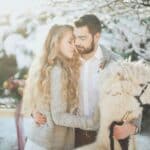 Winterhochzeit: Paar umarmt Alpaka im Schnee. Freie Trauung im Winter.