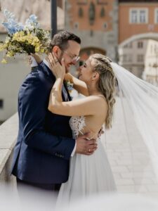 Das glückliche Paar Philipp und Antje umarmt sich an ihrem Hochzeitstag. Die Braut trägt ein wallendes Kleid und einen Schleier.