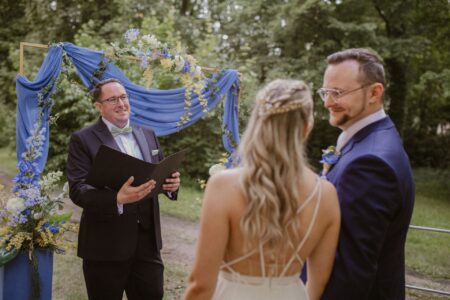Trauredner führt mit dem Paar eine Trauungszeremonie im Freien durch