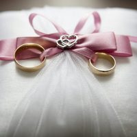 Eheringe auf Kissen mit rosa Schleifendetail